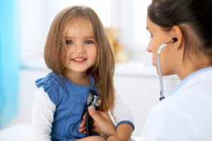 doctor checking young girl's heart rate