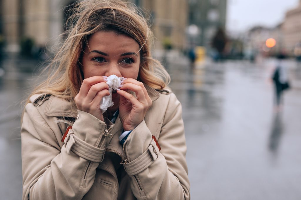 woman blowing nose outside