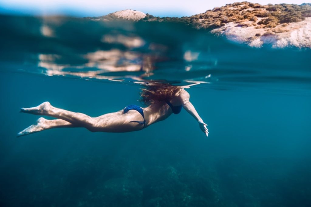 An underwater image of a woman swimming in the ocean.