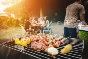 Grilled meat and vegetables on outdoor barbecue grill with flames, summer cookout setting