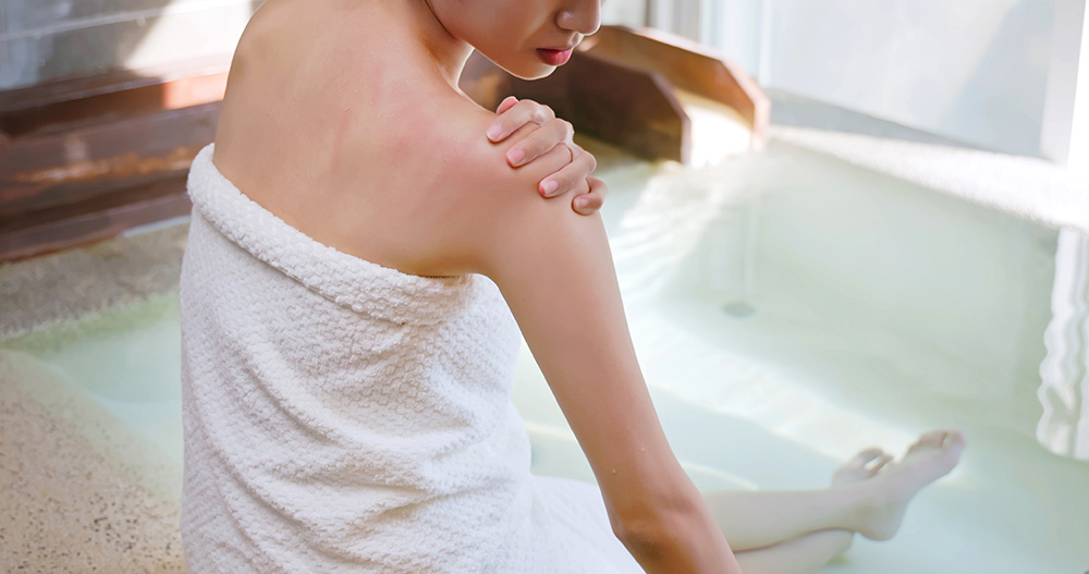 Woman in a hot spring examining a rash on her shoulder.