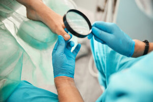 Surgeon inspecting a patient’s foot with a magnifying glass in an operating room.