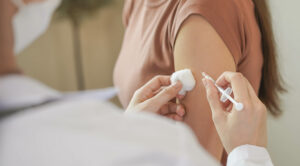 A health care provider giving a flu shot on a woman’s shoulder.