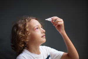 Child with pink eye applying eyedrops.